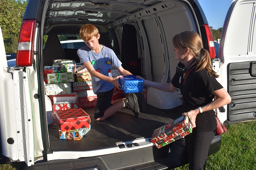 Lou and Amy Towery load shoeboxes full of donated gifts into vans to be dispersed by Meals on Wheels Plus Manatee.