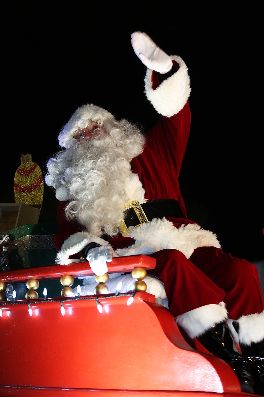 Santa Claus waves to cheering fans.