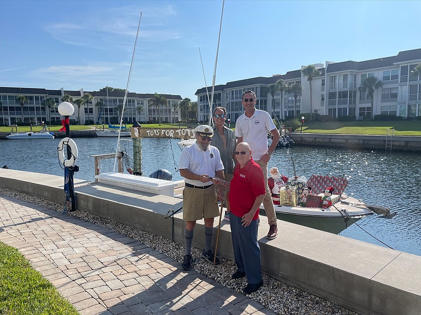Commodore Bill Coughlin donates the $5,280 check to Toys for Tots coordinator Jim Lamb. On the seawall, Frank Degregorio and Igor Solovyev are also pictured. Submitted