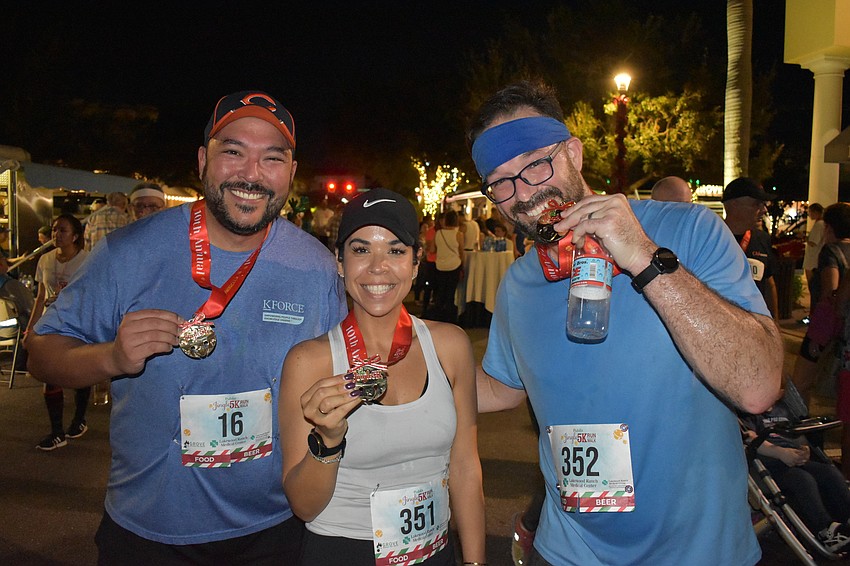 John Karas, Teresa Pelayo and Mike Pelayo, all of Lakewood Ranch, show off their medals after finishing the Jingle Run.