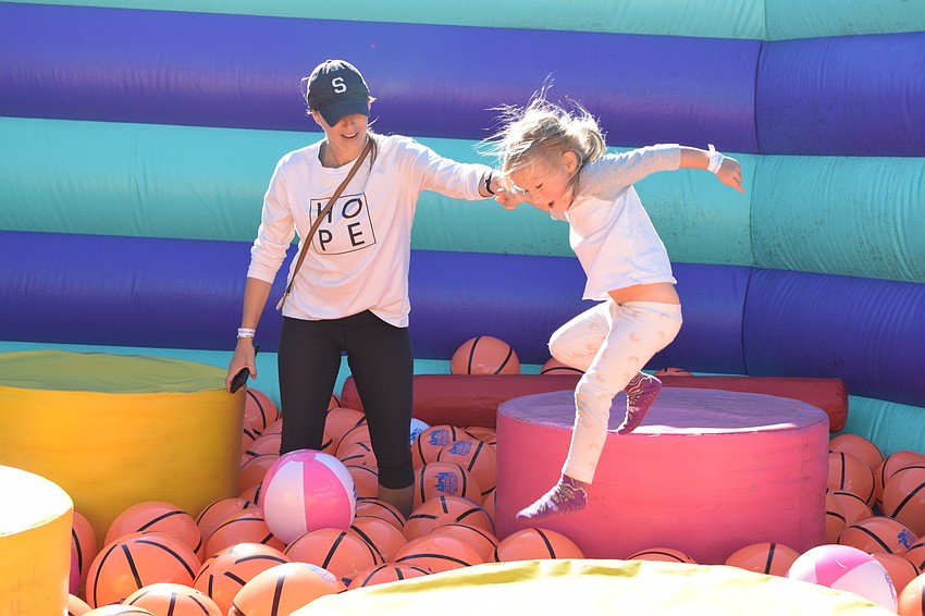 East County's Sarah Swift holds her 3-year-old daughter, Olivia Swift's, hand as she jumps into a sea of inflatable basketballs.