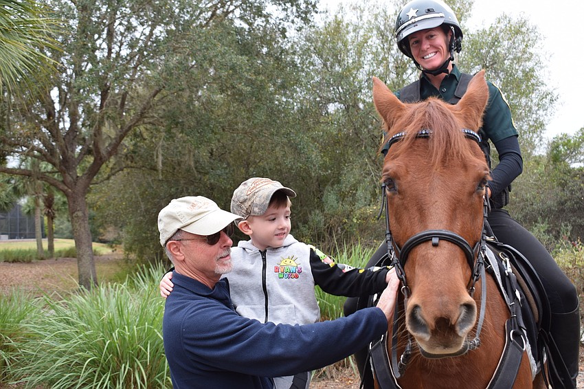 Peter Pino of Indigo lets his 5-year-old grandson Spencer get close to a horse ridden by Manatee County Sheriff's Office Deputy Lauren Bradley, who trains horses for the mounted patrol.