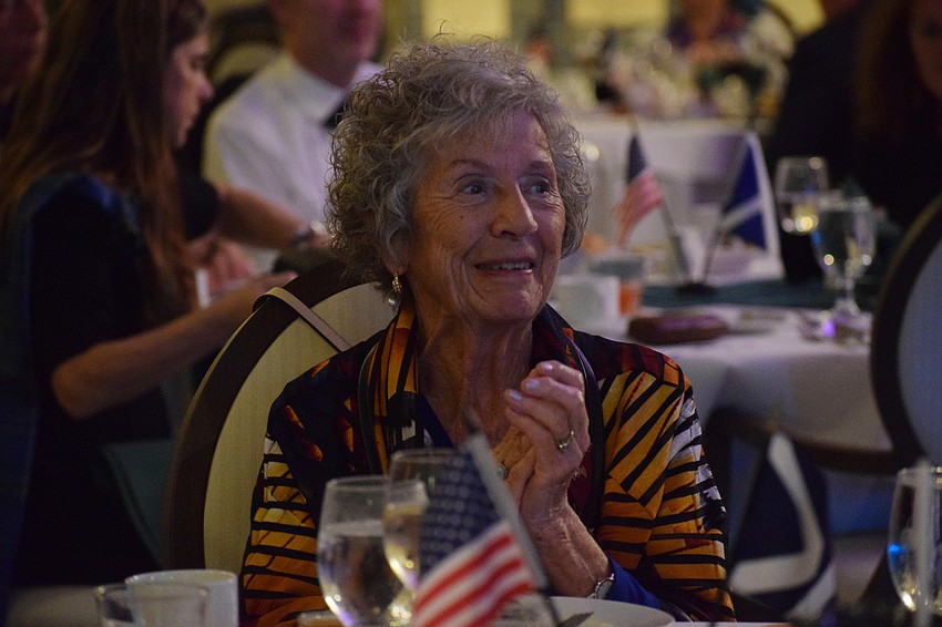 May Crawley, the honorary president of St. Andrew's Society of Sarasota, claps along to a song.