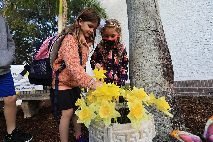 Elle Reuter and Segolene Gamble plant their pinwheels together.