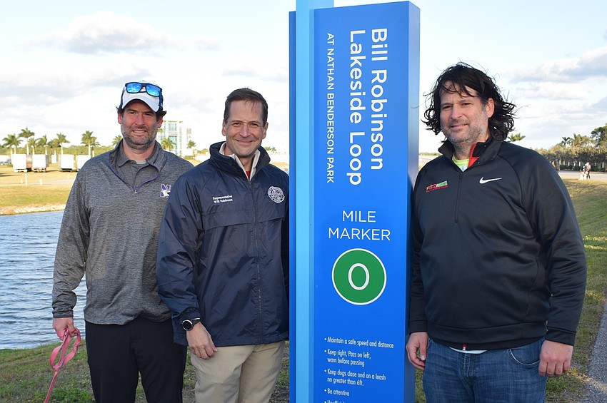 Wes, Will and Parks Robinson stand by one of five mile markers dedicated Jan. 29 to their late dad, Bill Robinson, on the Bill Robinson Lakeside Loop at Nathan Benderson Park in Sarasota.