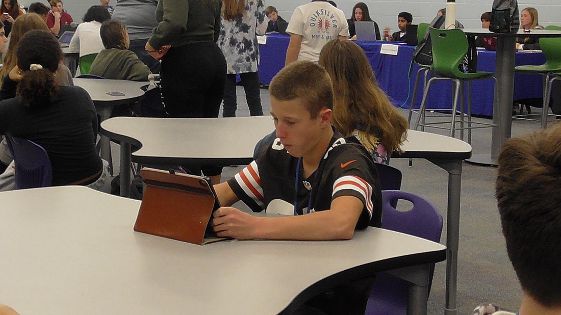 Trenton Huffman, a student at R. Dan Nolan Middle School, works on a tablet while sitting at one of the tables in the media center.
