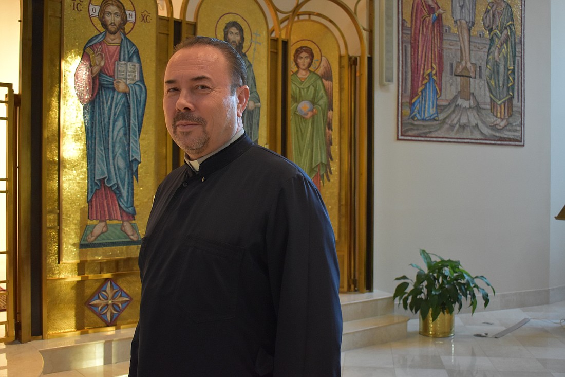 Father John Bociu stands in front of the icons at the entrance to the altar at St. Barbara Greek Orthodox Church.