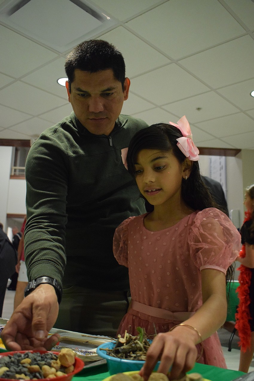 Luis Zaa and his daughter Kelly Zaa, who is in third grade, decorate a frame together.