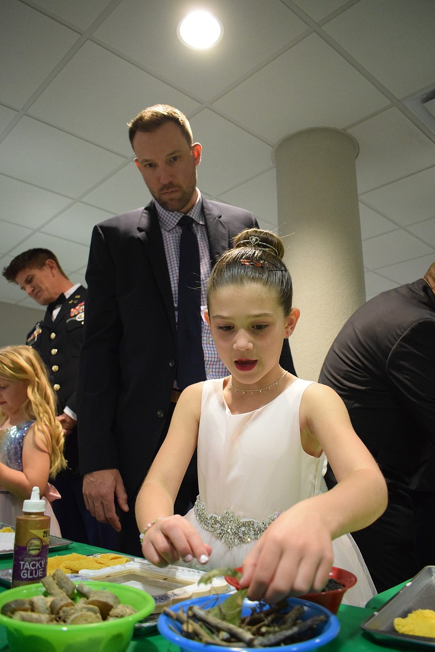 Jim Johnson helps his daughter Charlie Johnson, a kindergartner, decorate a picture frame.