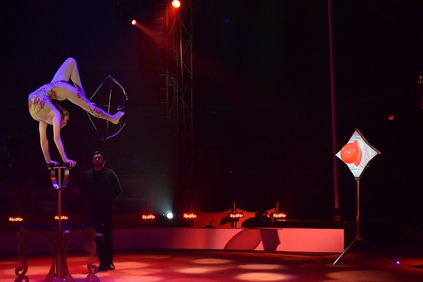 Elayne Kramer pops a balloon using a bow and arrow with her feet.