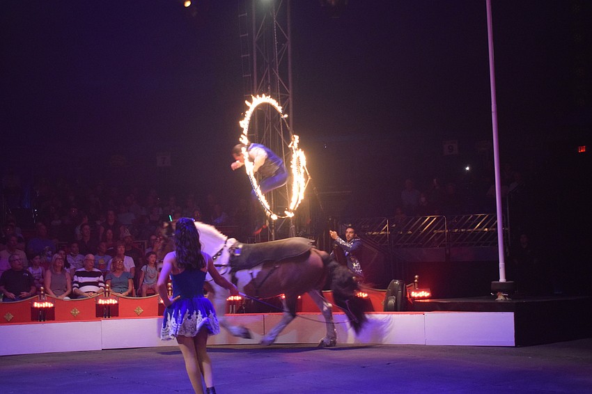 Caleb Carinci jumps through a hoop of fire before safely landing back on his horse.