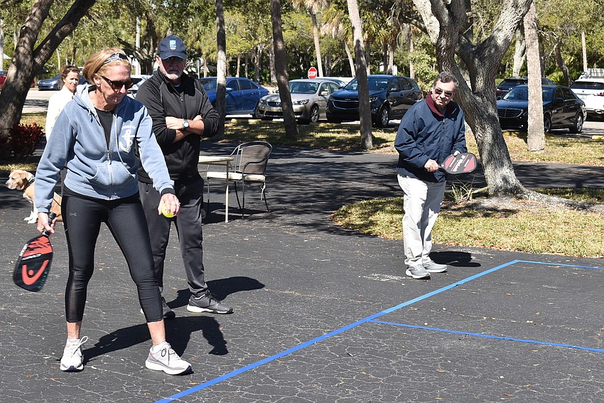 Rudell Hickey prepares to serve as Robby Reid looks on and Ron Ginsberg watches.