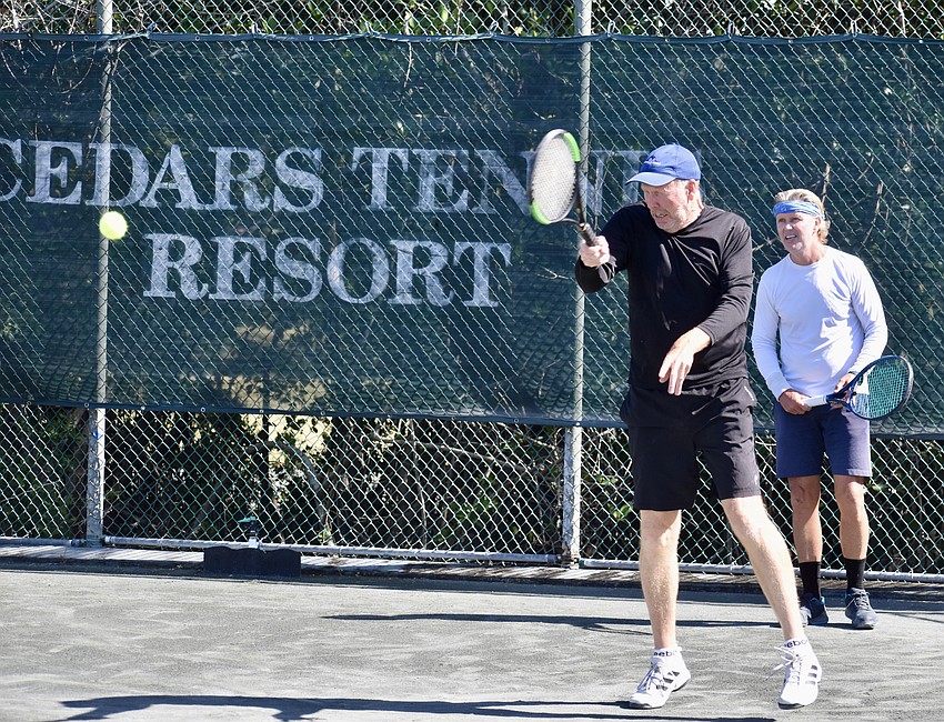 Clinic participant Mike Young delivers a return while Steve Willoughby awaits his turn.
