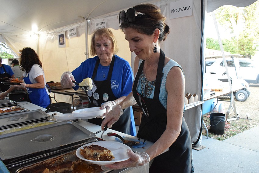 Greek Glendi volunteers Charlene Goranites and Elaine Drikakis prepare a plate of moussaka with rice and potatoes.