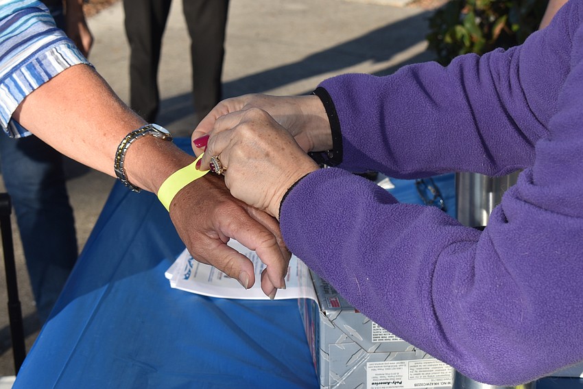 Irina LaRose fastens a band on an attendee at the entrance.
