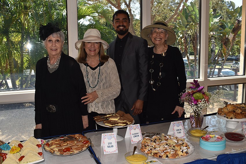 Sylvia Pastor, Kelli Veit, Michael Mendez and Nancy Cohen stand behind the table of food.