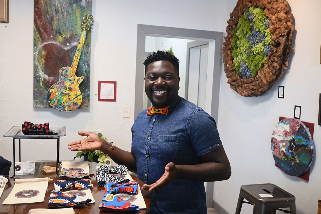 Travis Ray smiles and poses in front of his handiwork at Monark Custom Framing and Art Gallery. (Photo: Spencer Fordin)