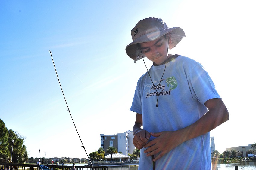 North Port's Evan Quinn, who is 13, puts a weight on his fishing line so he can cast farther into Lake Uihlein.