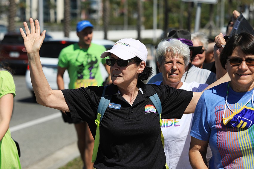 Project Pride board member Donna Hanley waves to passing drivers.