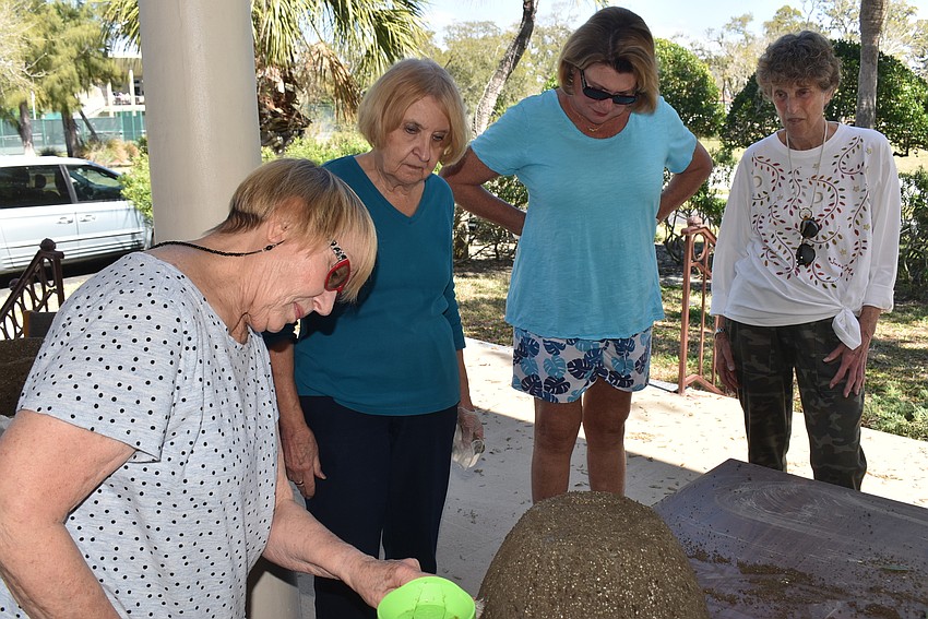 Marcia Gregg takes a closer look at a pot while Arlene Davis, Jan Marshall and Louise Millman look on.