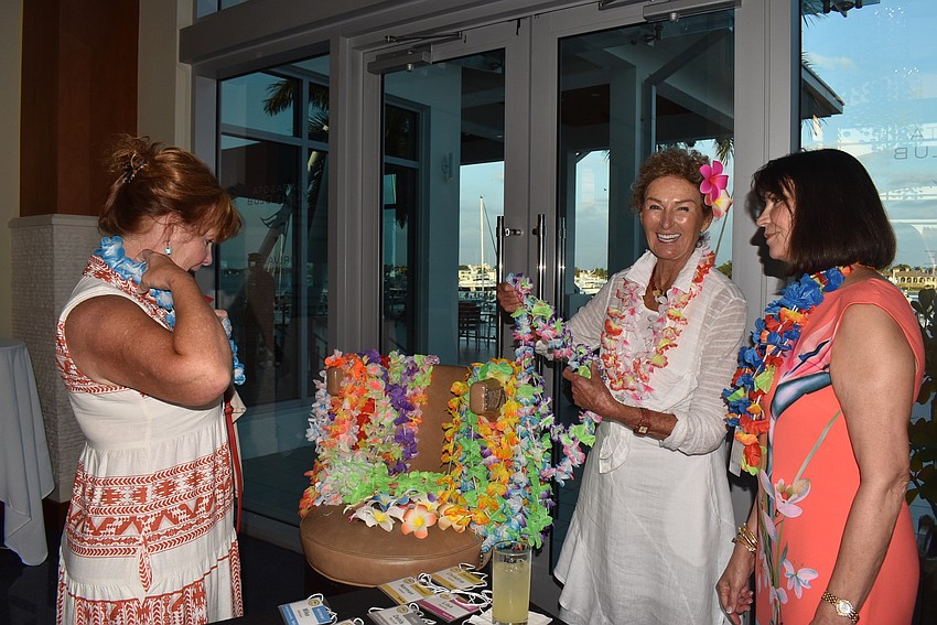Diane Adams dons a lei from Diana Kaslow and Josette Carter.