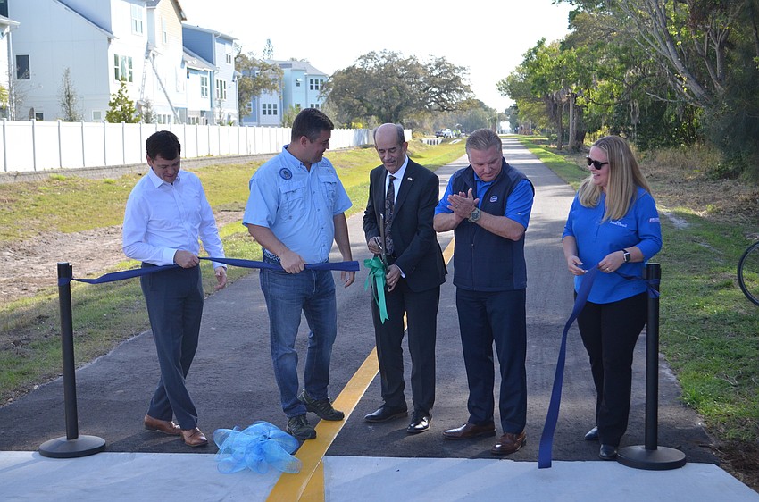 Commissioner Ron Cutsinger smiles after cutting a ribbon. He's flanked by Assistant County Administrator Brad Johnson, county commissioners Christian Ziegler and Mike Moran and Nicole Rissler.