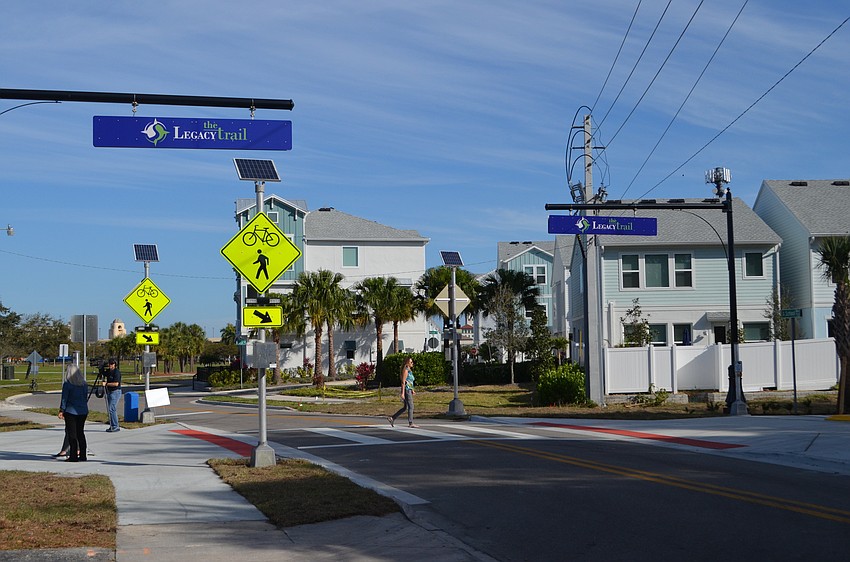 A woman crosses the street to watch the ribbon-cutting that marked the opening of Legacy Trail's Segment 3.