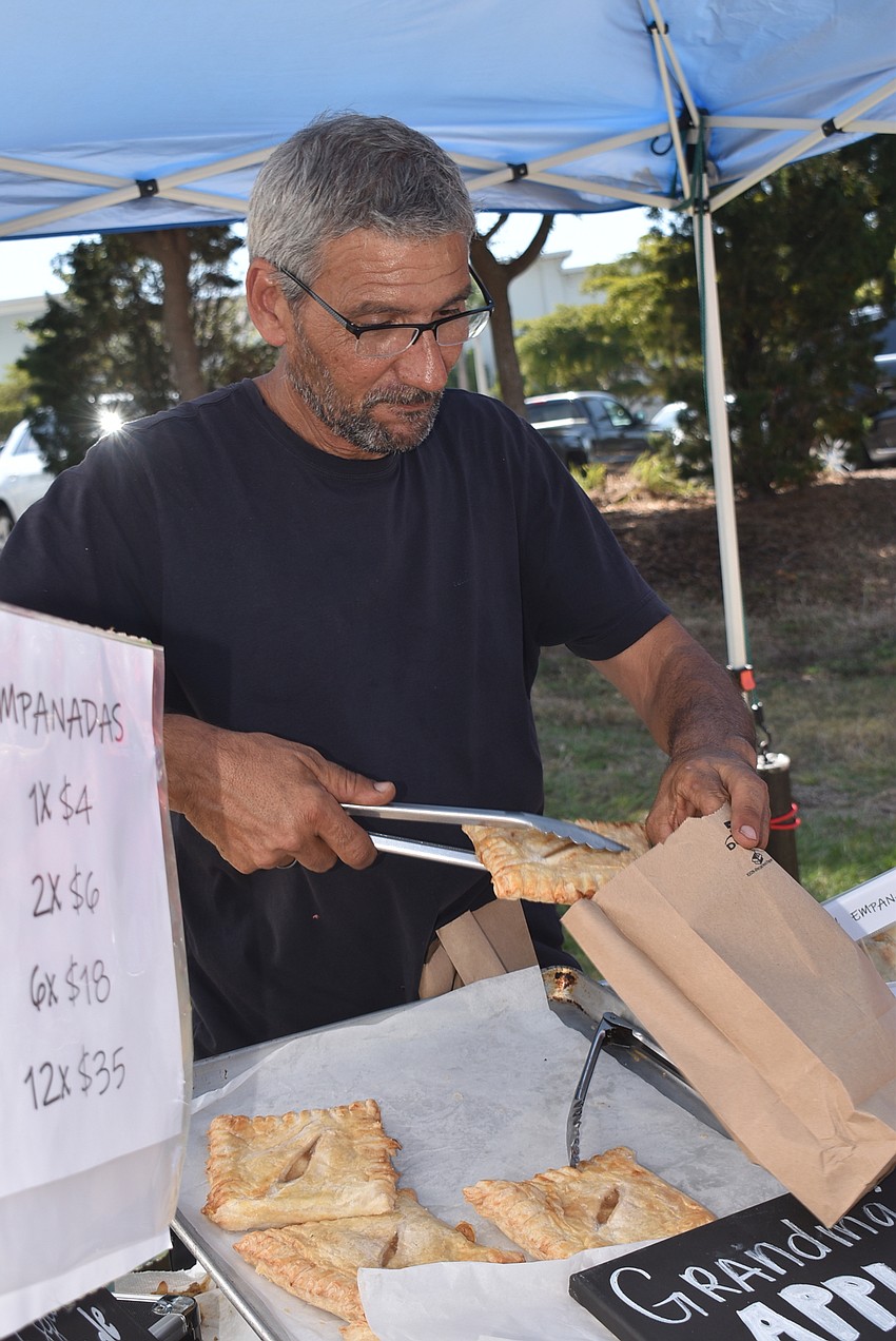 Ariel Asain puts an empanada in a bag.