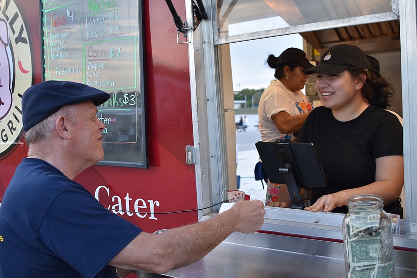 Sarasota's Terry Grady, a festival volunteer, buys a treat from Giovanna Trejo of Happy Belly Tacos.
