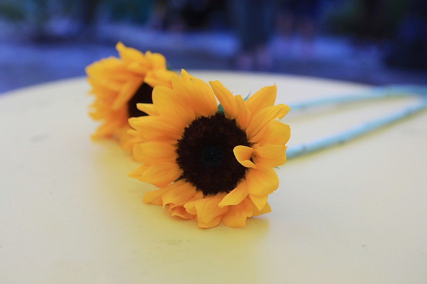 Attendees carry sunflowers as a gesture.