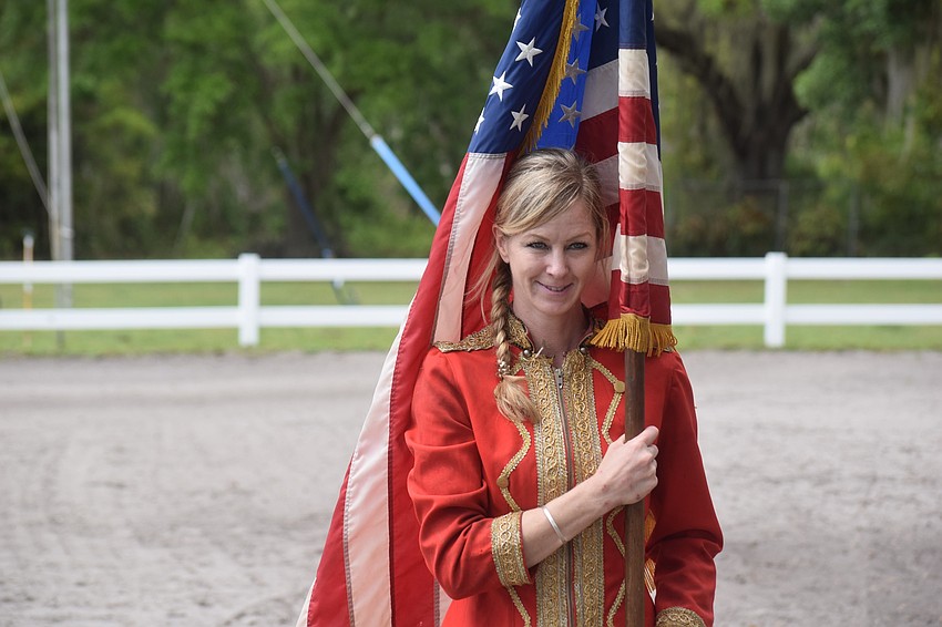 Angela West, a rider for Herrmann's Royal Lipizzan Stallions, presents the flag before the show.