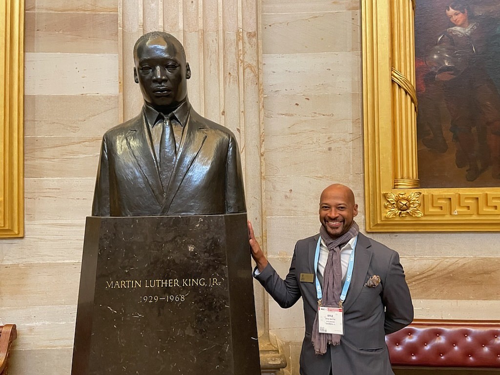 Commissioner Kyle Battie stands next to a Martin Luther King sculpture in the Capitol. (Courtesy photo)