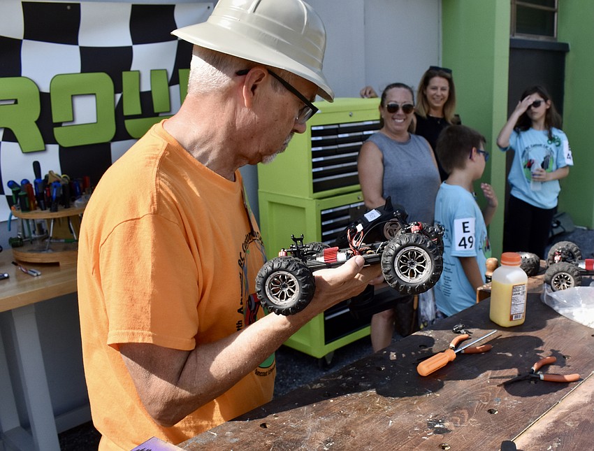 Volunteer Gary Morin helps diagnose a technical issue on a car belonging to Gary Morinvol and Asher Woods. It won the next race.