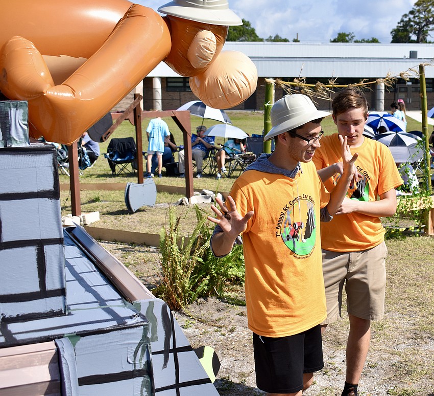 Volunteer worker Diego Morales helps secure an inflatable monkey to a race track obstacle.