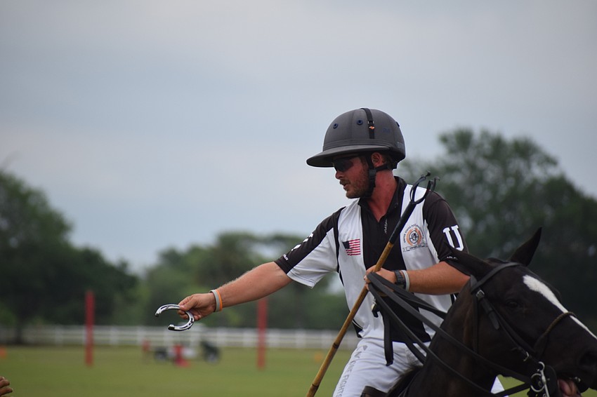 After a horse lost a shoe, Umpire Josh Shelton takes it off the playing field.