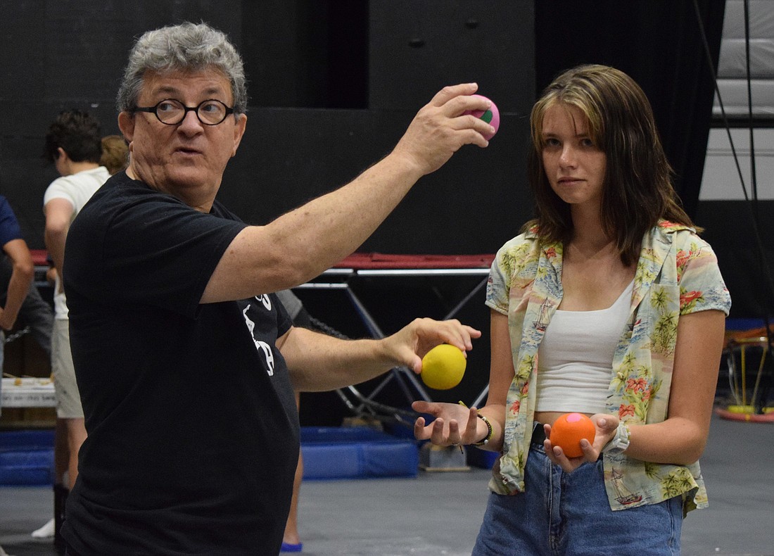 Aaron Watkins, a coach for the Circus Arts Conservatory, helps junior Emily Peterson understand how she can juggle multiple balls at once.