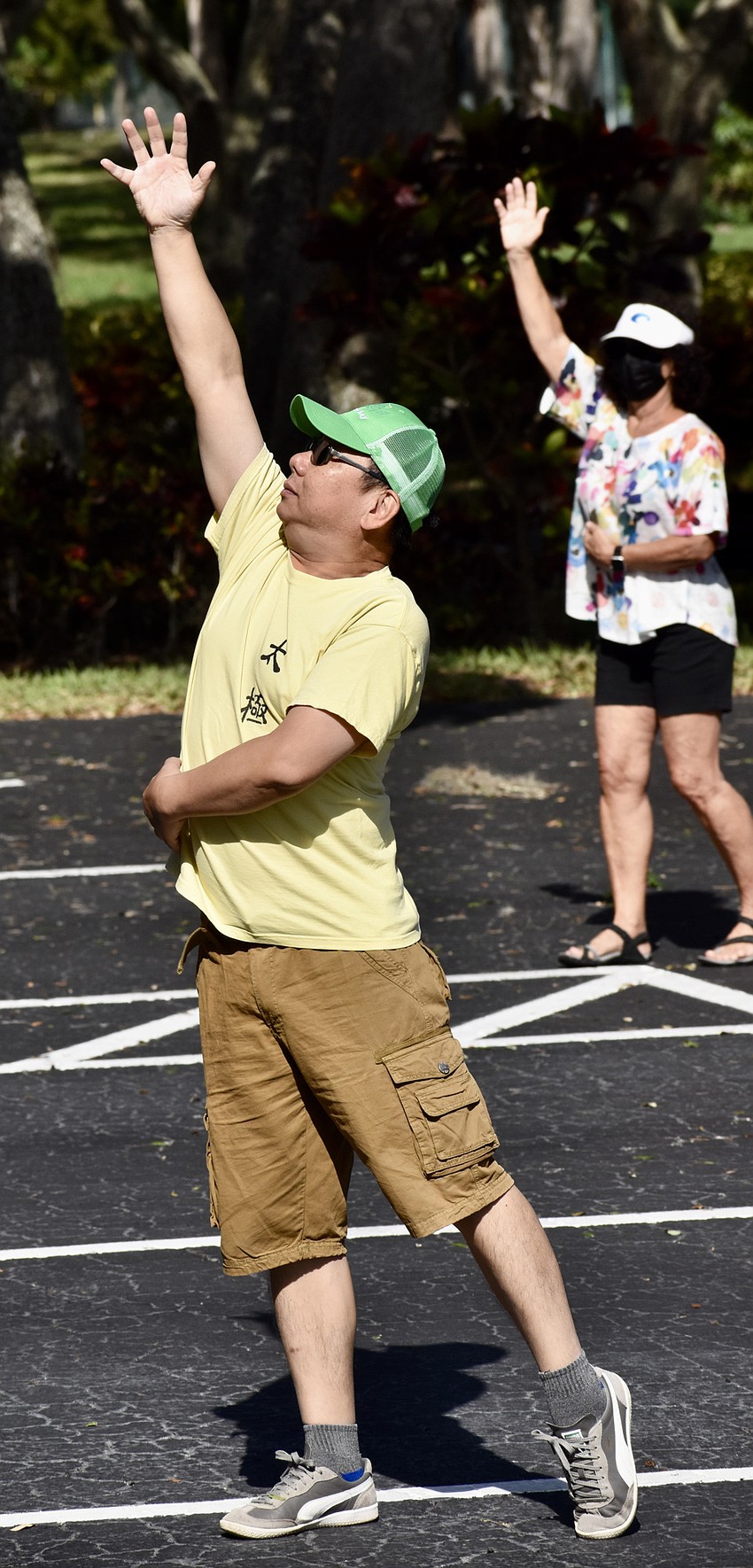 Master Max Yan performs a tai chi move, and Sue Ferrara does the same.