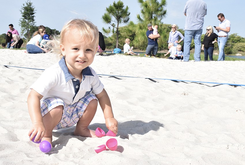 University Park's Callan Putt, who is 1, has fun playing with eggs in the sand after the egg hunt.