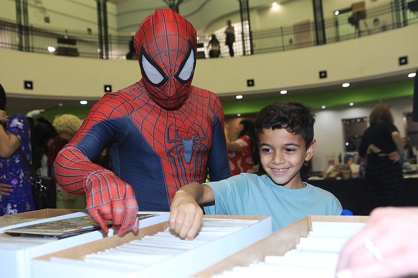 Michael Pelaez as Spider-man flips through comics with Jeriah Garcia at the Descent Into Gaming table.