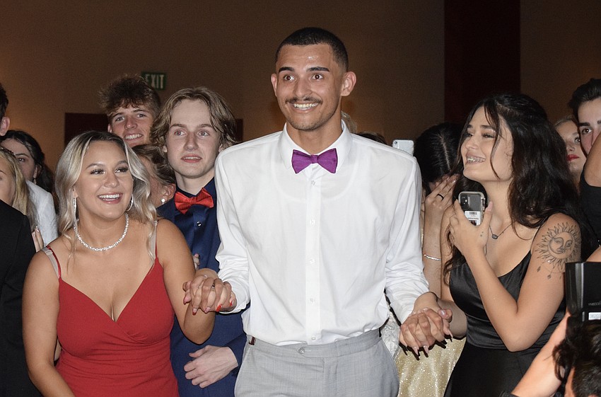 Senior David Kochaniec (center) holds onto the hands of Marisa Cantarella and Kianna Arrazola as he is named prom king.
