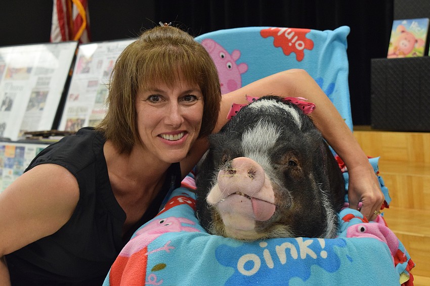 Bunni Roberts, a pre-K teacher, gets her photo taken with Daisy, a pig.