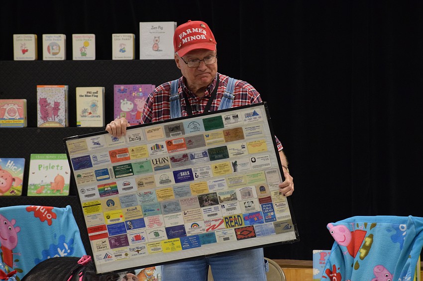 Paul Minor shows students all the library cards his pig, Daisy, has received from libraries across the country.