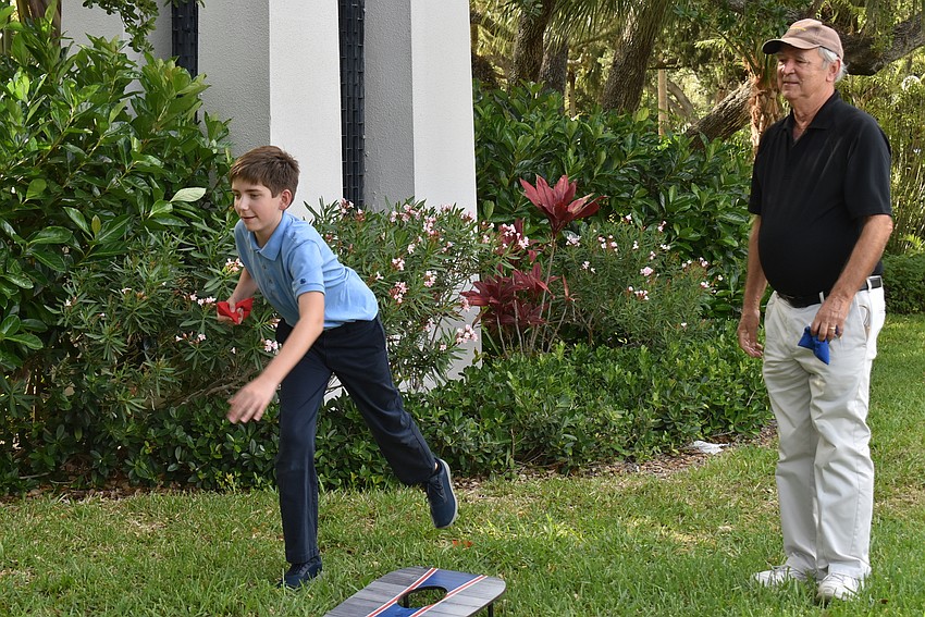 Elijah Marshall tosses a corn hole bag while Ed Upshaw looks on.