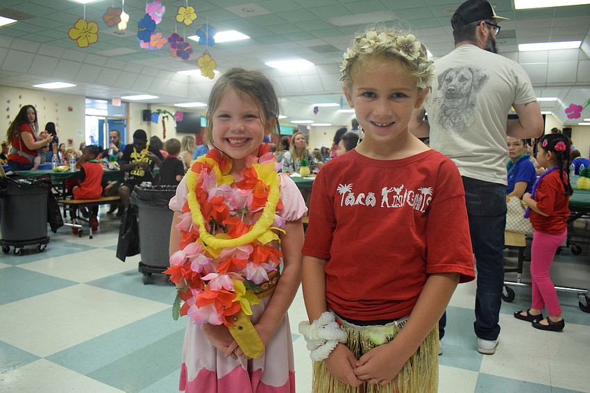 Kindergartners Charis Hogue and Vivianne Rissler show of their luau attire before eating dinner with their families.
