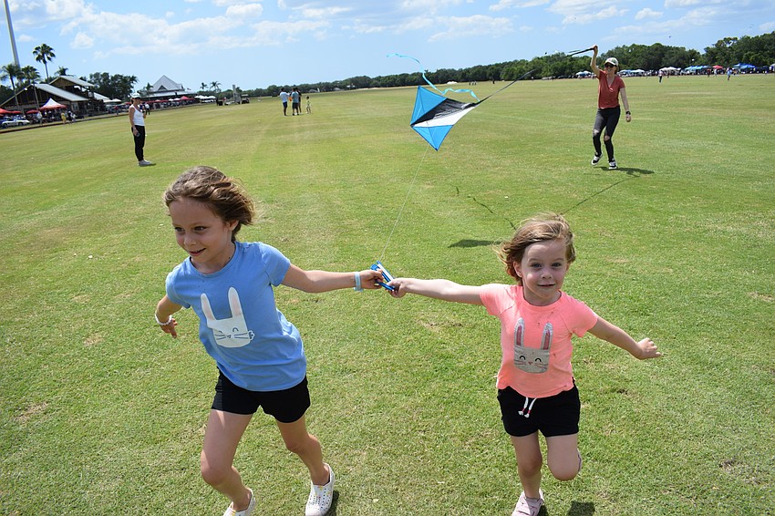 Everly and Isla Binnie race forward to make their kite take flight while their mom, Jessica Binnie, gives the kite a lift from behind. The kites were part of a Children's Cancer Center fundraiser at the Sarasota Polo Club.