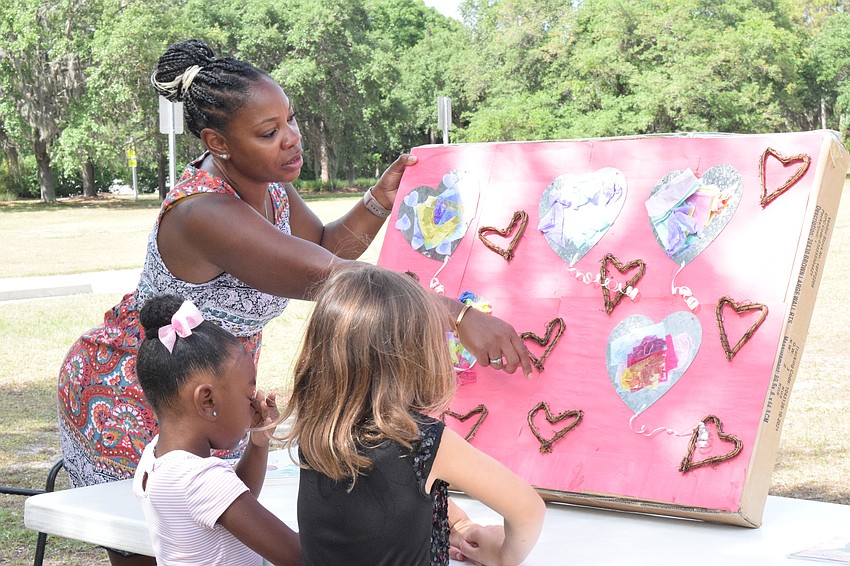 Shenicka Claxton, a World of Wonder Academy leader, shows students Kristina Claxton and Hope Fisher the artwork they did on Valentine's Day.