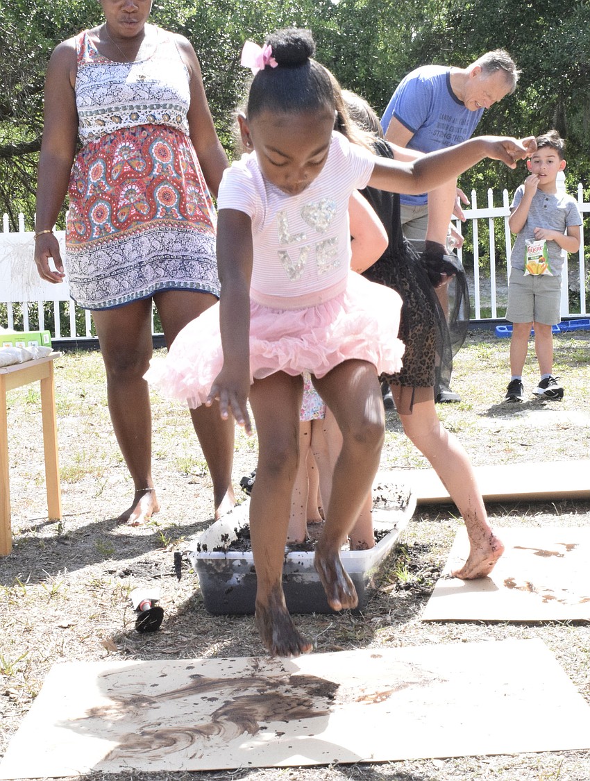 Kristina Claxton jumps out of the mud bin and onto a piece of cardboard to make art. 