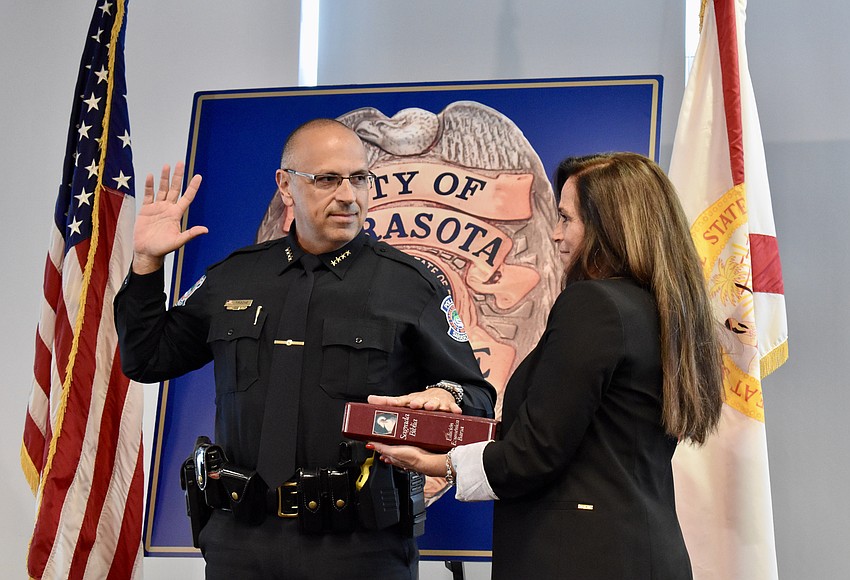 Rex Troche takes the oath of office while his wife, Kelly, holds the Bible.