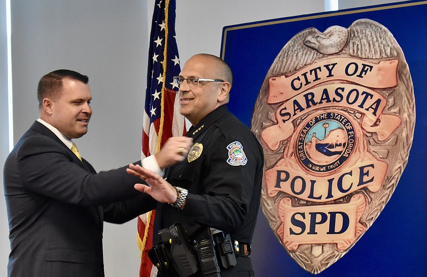 Deputy City Manager Pat Robinson jokingly adjusts Chief Rex Troche's tie and new gold badge.