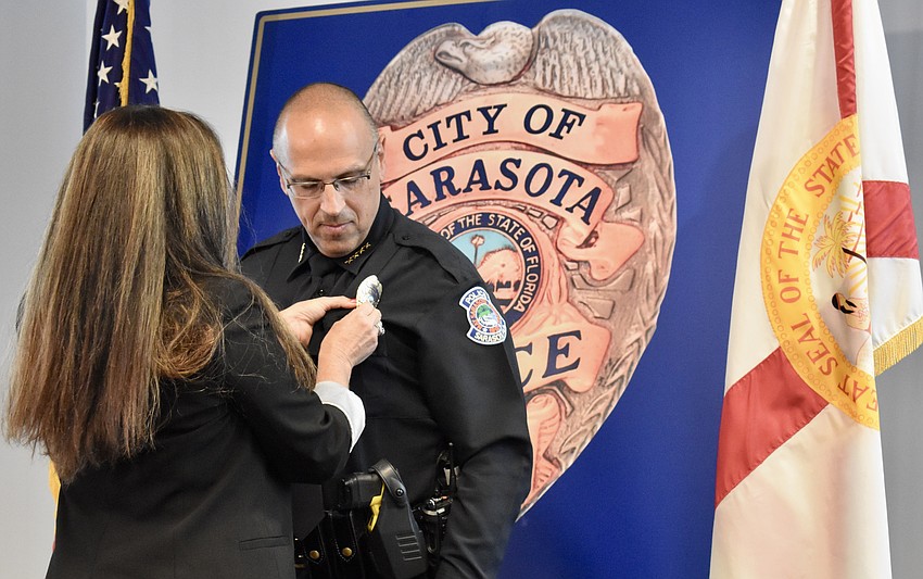 Kelly Troche pins the gold badge on the uniform of Chief Rex Troche.